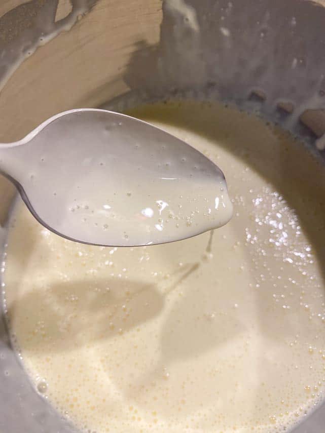 NY Style cheesecake batter will be thin, as seen here dripping off a spoon