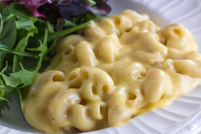 closeup of easy stovetop mac and cheese on white plate with green salad