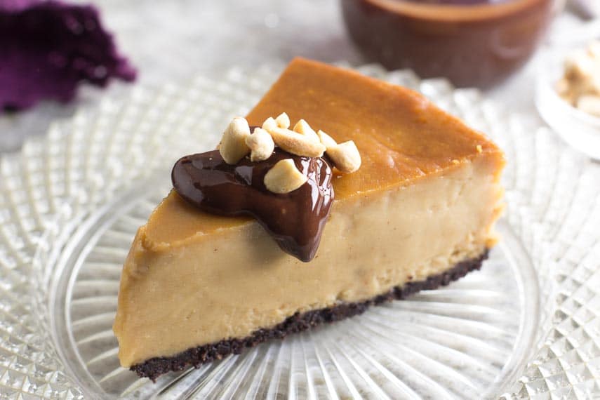 slice of frozen low FODMAP peanut Butter cheesecake with chocvolate sauce on top on cut-glass plate