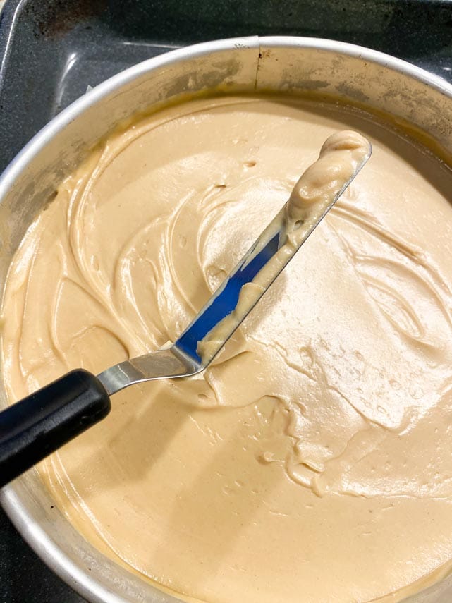 using small offset spatula to spread peanut butter cheesecake batter in pan
