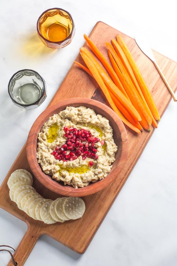 vertical image of low FODMAP eggplant dip in wooden bowl garnished with pomegranate seeds
