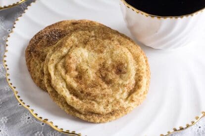 Closeup of Low FODMAP Snickerdoodles on white plate with cup of coffee alongside
