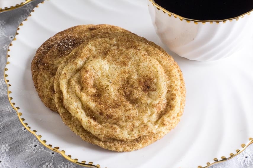 Closeup of Low FODMAP Snickerdoodles on white plate with cup of coffee alongside. Gluten-Free Christmas Cookies everyone will love