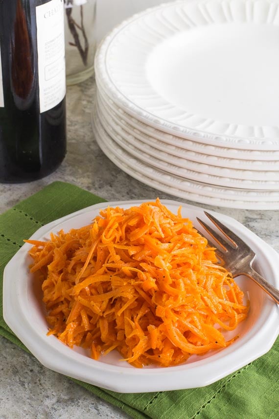 Low FODMAP Grated Carrot Salad on white plate; green napkin underneath, white plates alongside