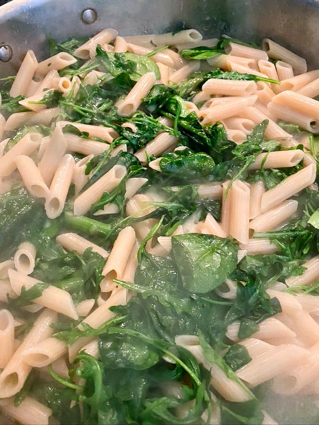 low FODMAP Pasta Primavera cooking; arugula and spinach cooking down