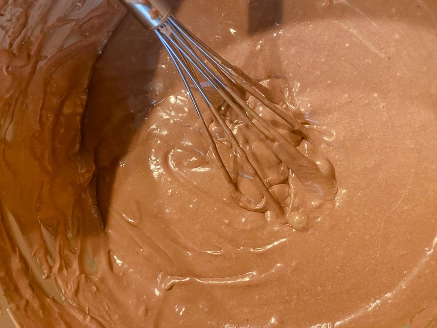 Using a balloon whisk and whisking by hand to ensure a rich, creamy, blended chocolate cheesecake batter
