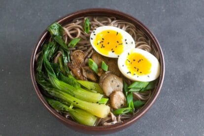 Low FODMAP Soba Miso Soup with Bok Choy and Jammy Eggs in brown ceramic bowl