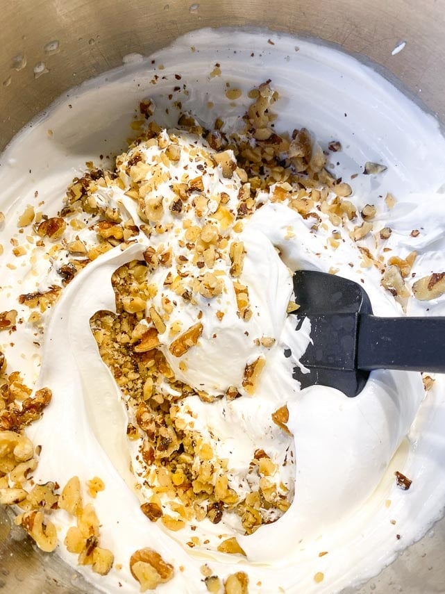 folding the sifted walnuts into the meringue with silicone spatula