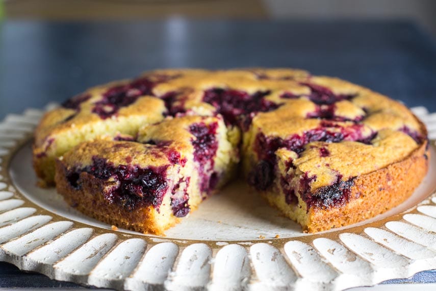 Low FODMAP Cornmeal Berry Snack Cake with berries on a decorative wooden plate