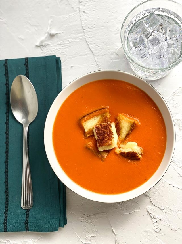 Low FODMAP Cream of Tomato Soup in white bowl; teal napkin