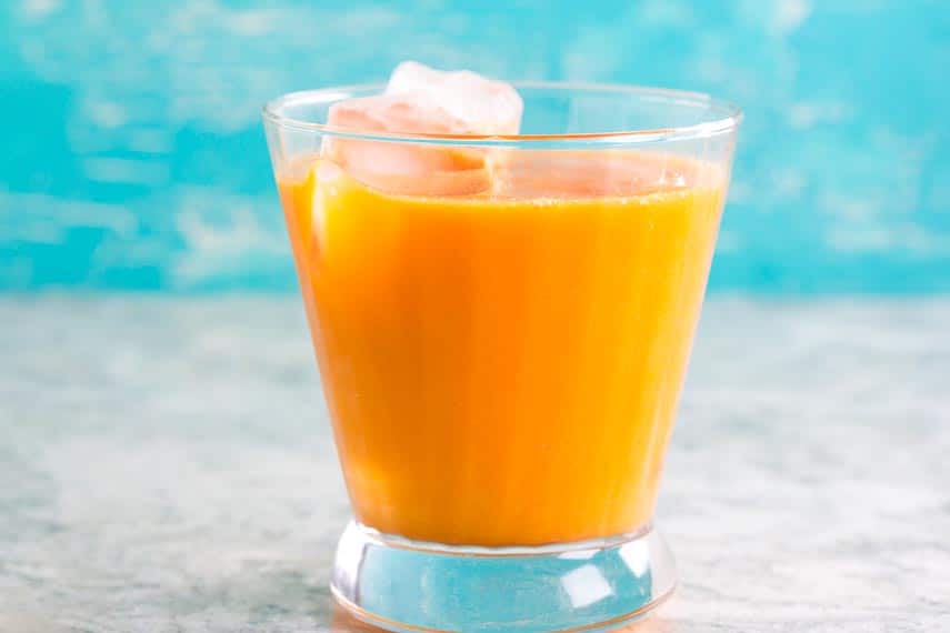 Low FODMAP Orange Carrot Juice in glass against aqua background