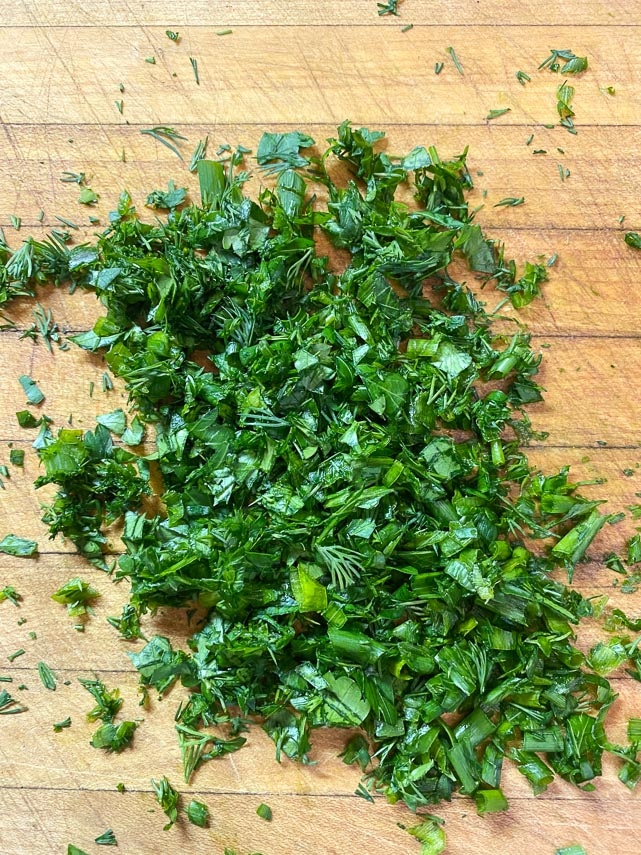 chopped herbs on wooden board for Low FODMAP Ranch Dressing
