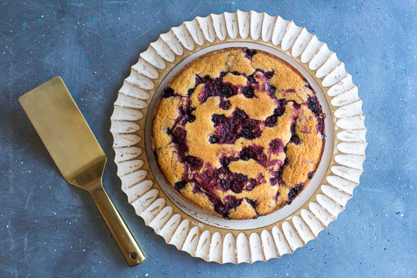low FODMAP Cornmeal Berry Snack Cake on wooden platter with gold server alongside
