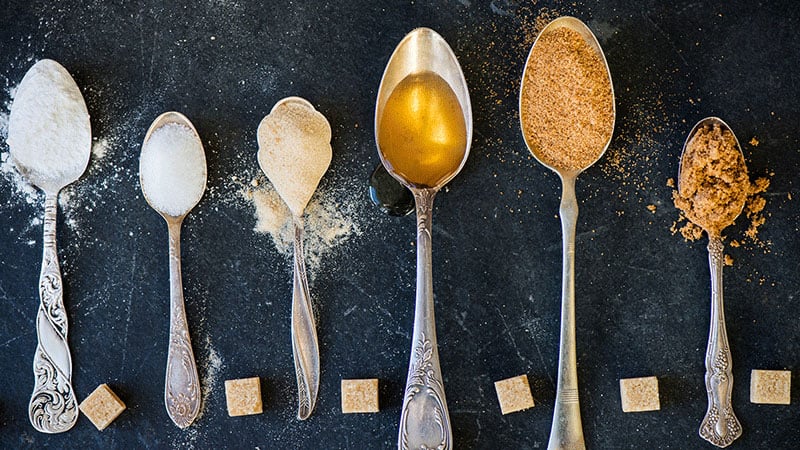 Assorted sweeteners in spoons on dark background