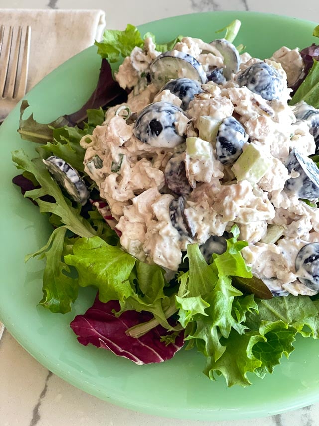 Low FODMAP Chicken Salad with Grapes and Almonds on a bed of lettuce on a green plate