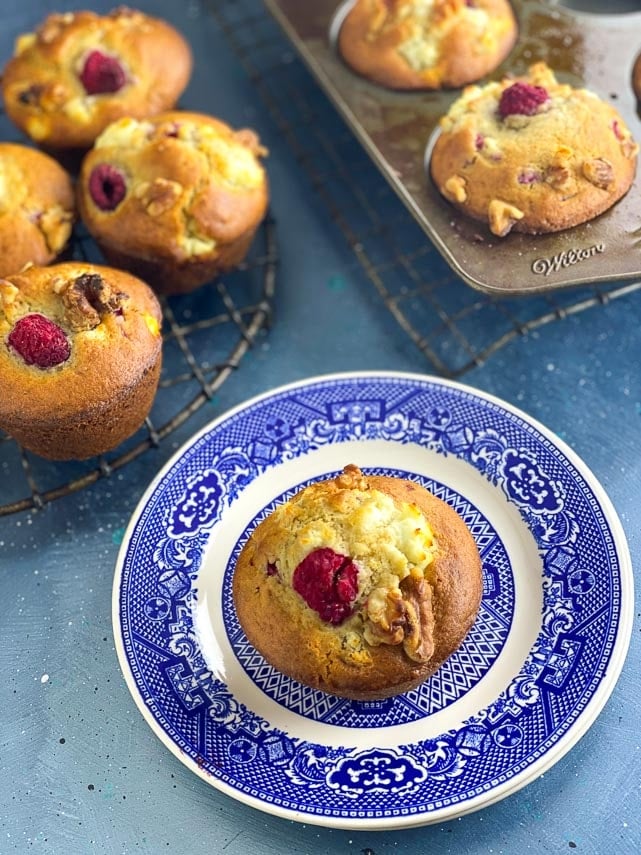 Low FODMAP Olive Oil Muffins with Goat Cheese, Walnuts and Raspberries in a round antique cooling rack; blue backdrop and on blue plate 2