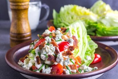Low FODMAP Wedge Salad slathered with blue cheese dressing on a brown ceramic plate