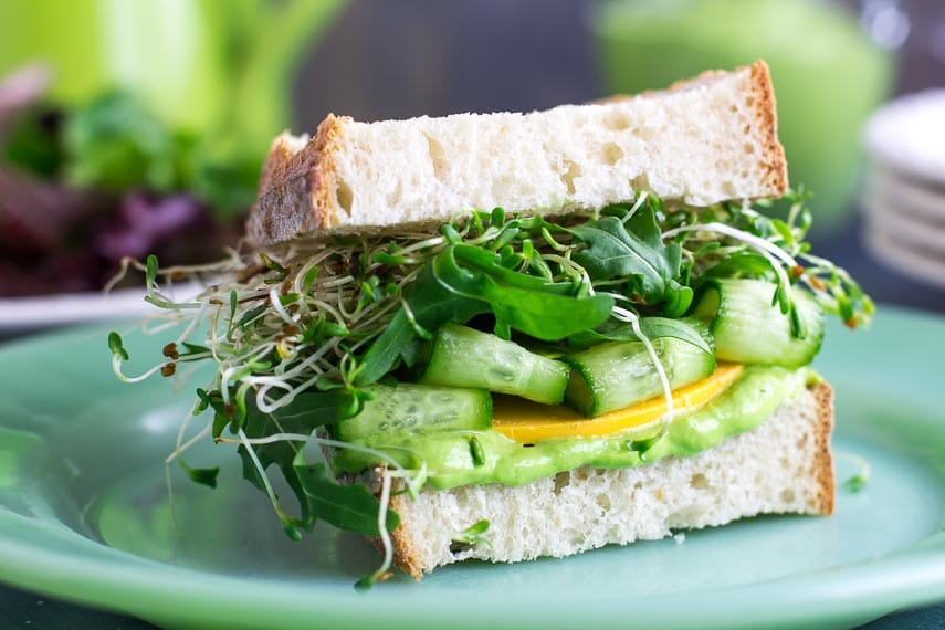 closeup VEGAN Low FODMAP Avocado Green Goddess Veggie Sandwich on green plate- a low FODMAP vegan recipe