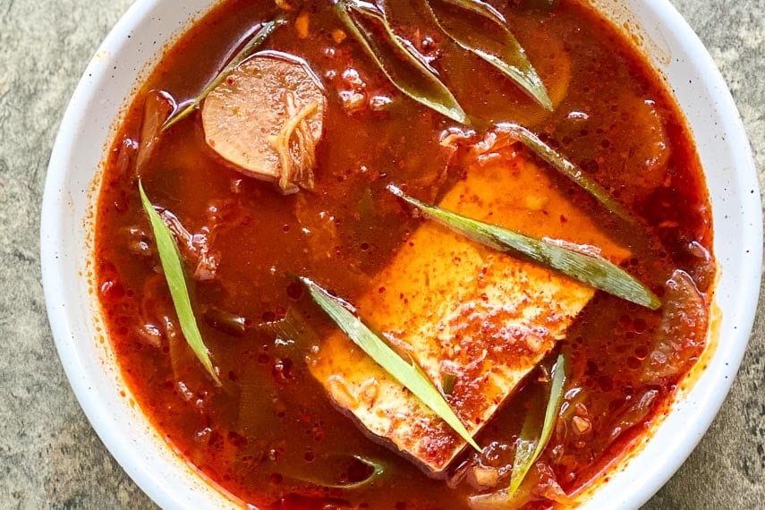 closeup low FODMAP Kimchi & Tofu Stew in white bowl on stone surface