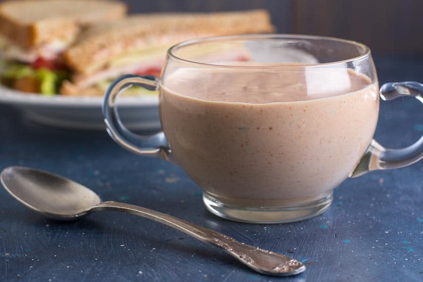 horizontal image of Low FODMAP Russian Dressing in a clear glass bowl with handles; blue backdrop