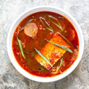 low FODMAP Kimchi and Tofu Stew in white bowl on gray stone surface