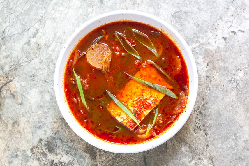 low FODMAP Kimchi and Tofu Stew in white bowl on gray stone surface
