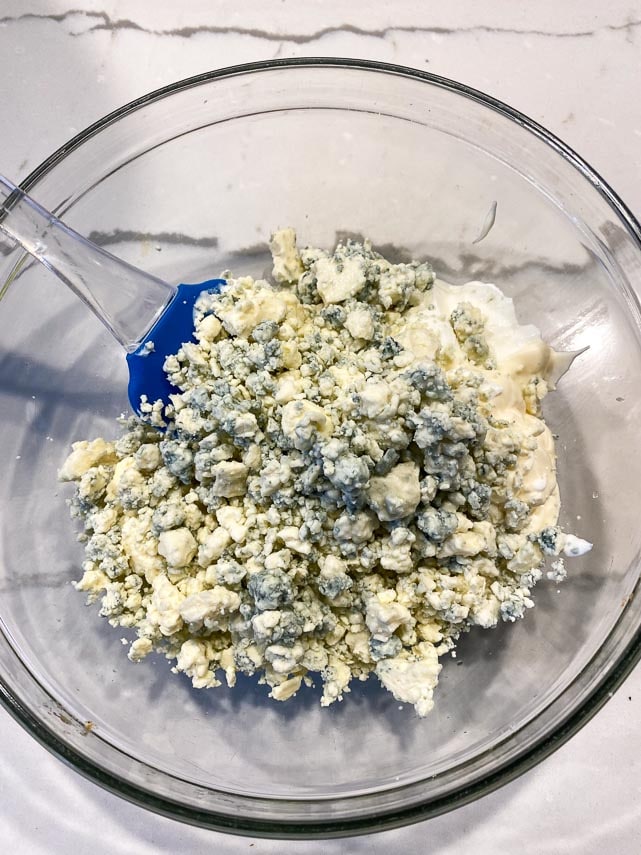 mixing blue cheese dressing ingredients together in a clear glass bowl