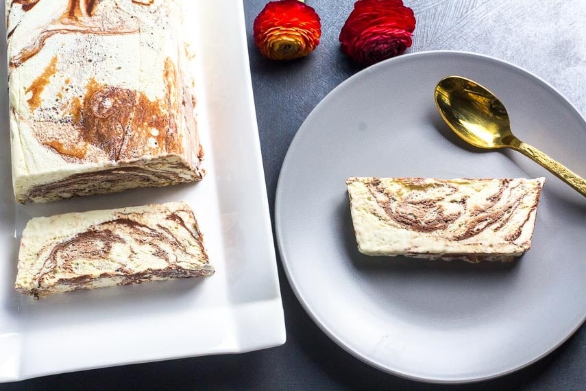 overhead of low FODMAP semifreddo; whole loaf on white platter; slice on gray plate; gold spoon_