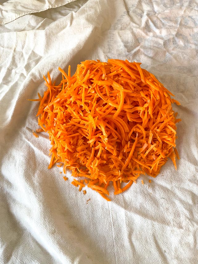 shredded carrots about to be squeezed in a tea towel