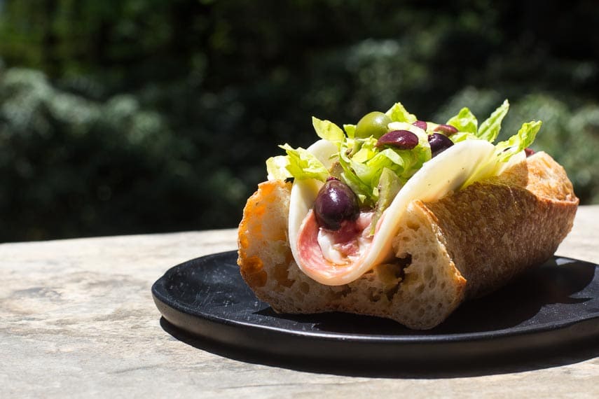 side view Low FODMAP Italian Sub on a black woode plate, outside on stone surface