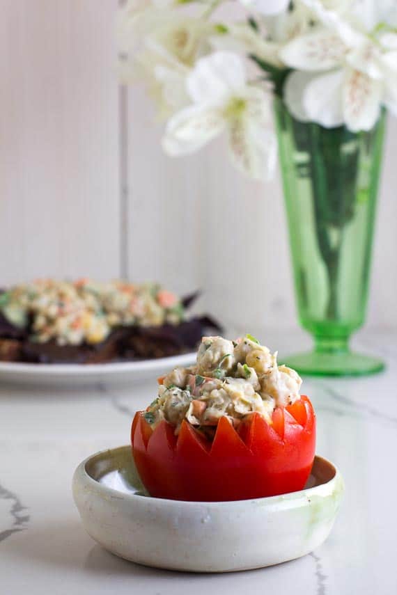 vegan low FODMAP Chickpea salad stuffed into a hollowed out tomato in a ceramin dish