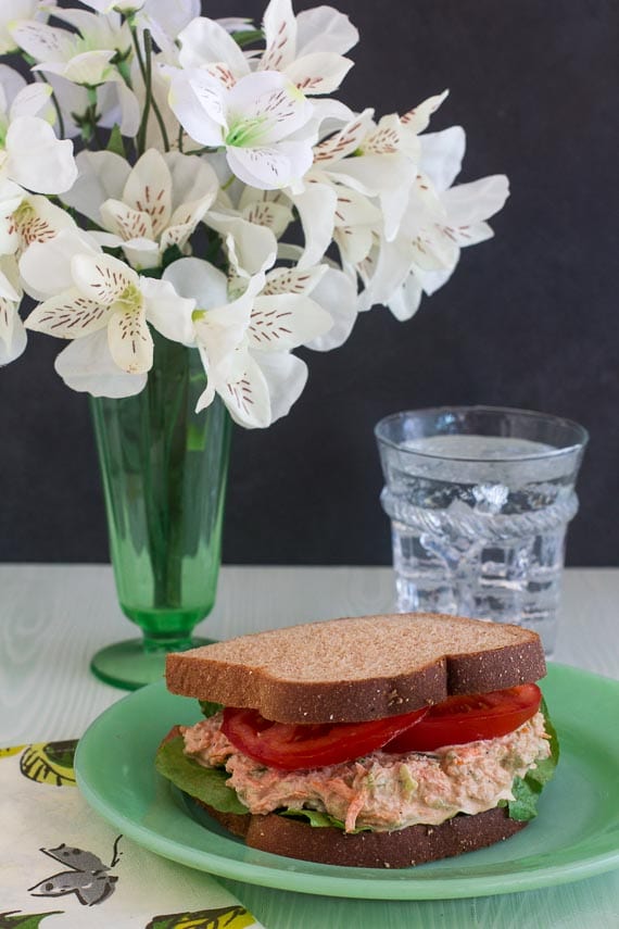 vertical image of low FODMAP cajun tuna salad sandwich on green plate; glass of water