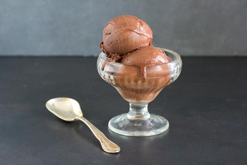 Low FODMAP Chocolate Sorbet in an ice cream dish with an ice cream spoon on a dark surface