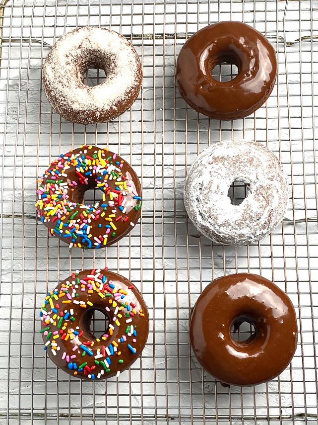 Low FODMAP baked Chocolate Doughnuts with various toppings on rack