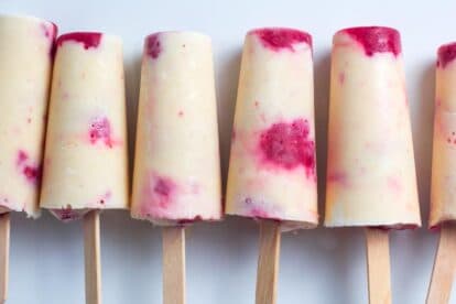 Low FODMAP peaches & cream popsicles with raspberries, close up, lined up on white plate_