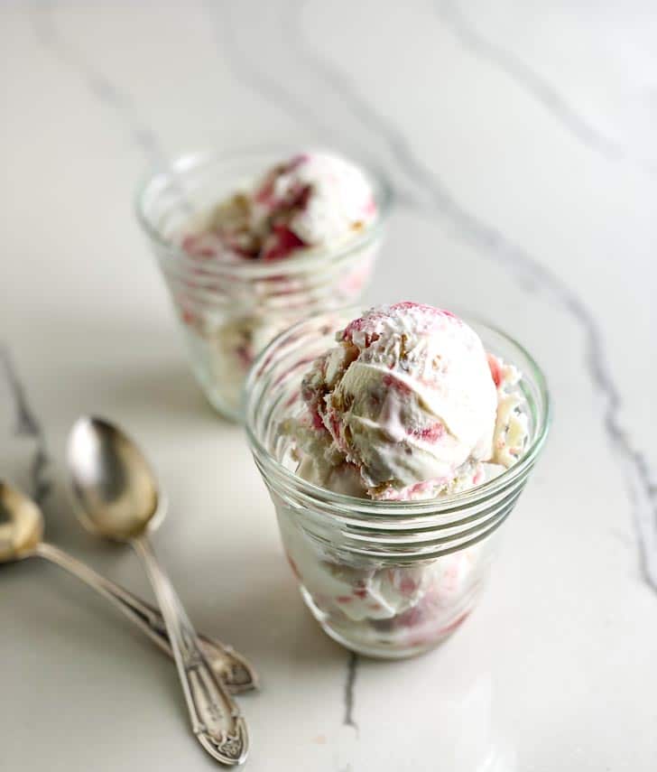 close focus image of clear cups of low FODMAP Rhubarb Crumble Ice Cream with silver spoons on white marble