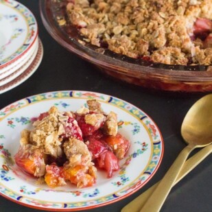 horizontal image of low FODMAP strawberry peach crisp on a decorative plate and in pie plate in background