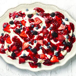 horizontal image of low FODMAP Mixed Berry Slab Pavlova on decorative oval plate; white background