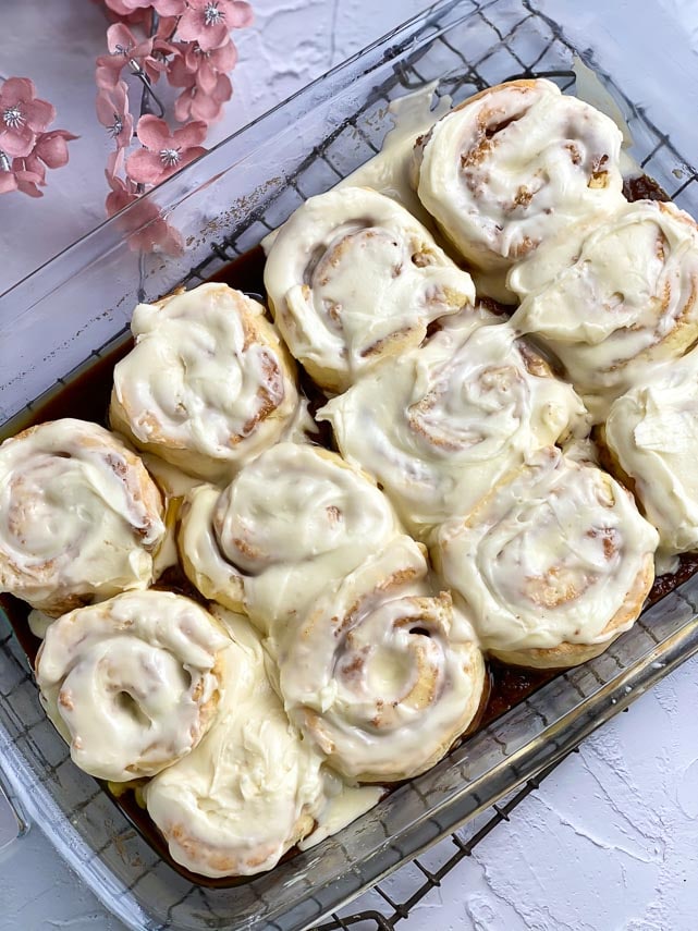 low FODMAP Cinnamon Rolls slathered with lactose-free cream cheese frosting in pan on rack