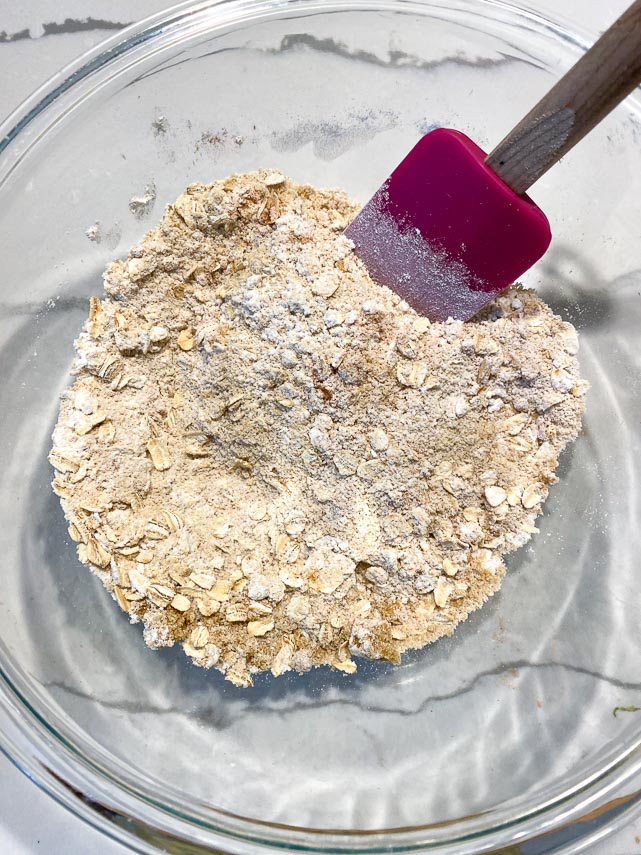 mixing together dry ingredients for Vegan Low FODMAP Crisp Topping ingredients in a glass bowl