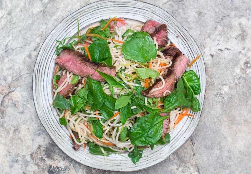 overhead image of Low FODMAP Thai Basil Steak Salad on rustic round white plate