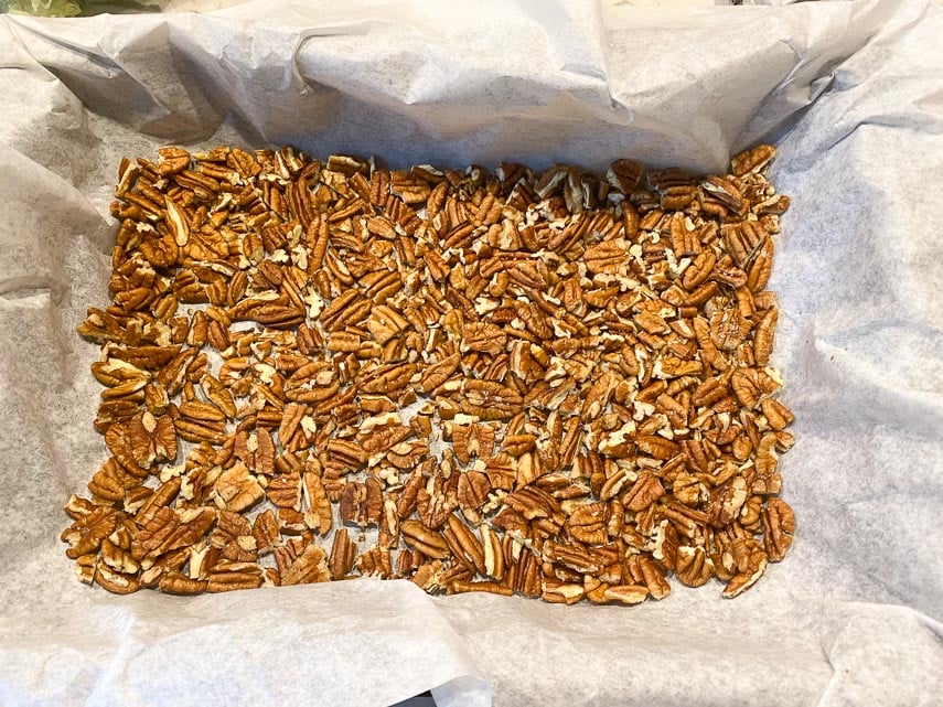 pecans in parchment lined pan for sticky buns