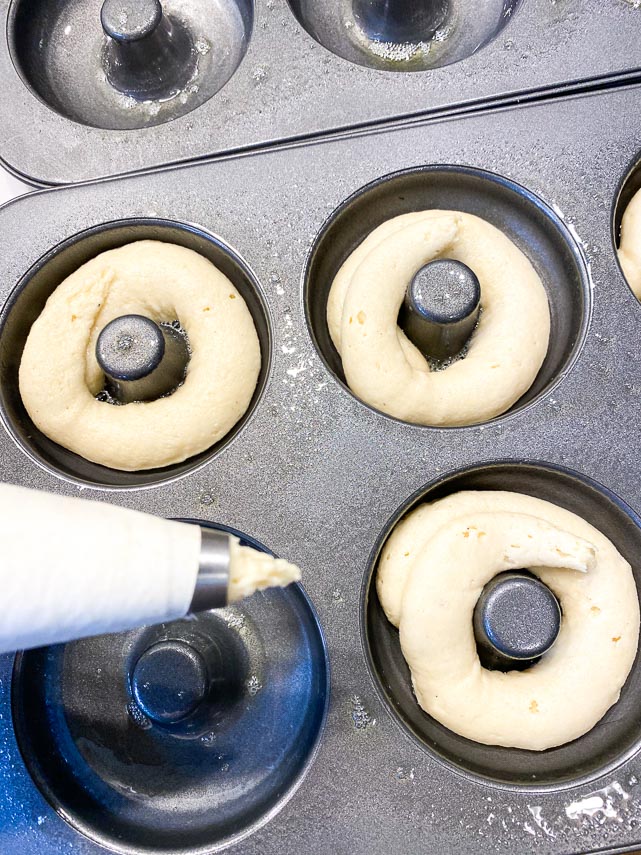 piping batter into pans for low FODMAP Baked Doughnuts using pastry bag and round tip