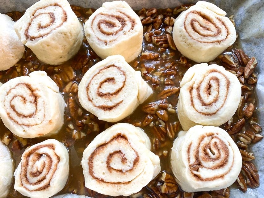 raw sticky buns on top of sticky sauce in pan ready to bake