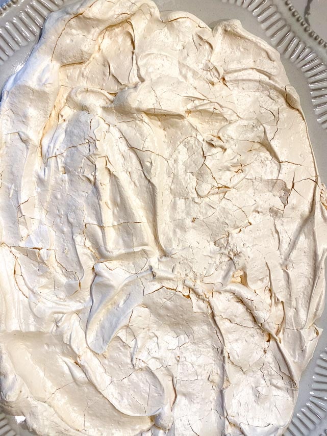 slab pavlova meringue disc on large serving platter, gently crushed to facilitate serving