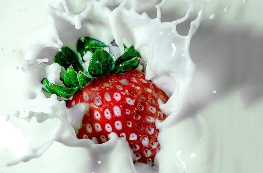 strawberry splashing in a bowl of cream