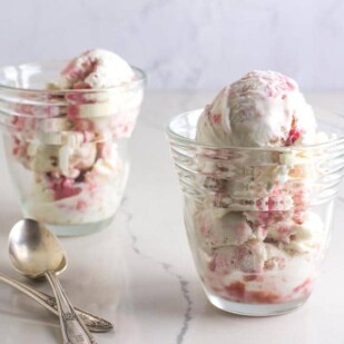 two glass dishes holding low FODMAP Rhubarb Crumble Ice Cream; silver spoons alongside on a white marble counter