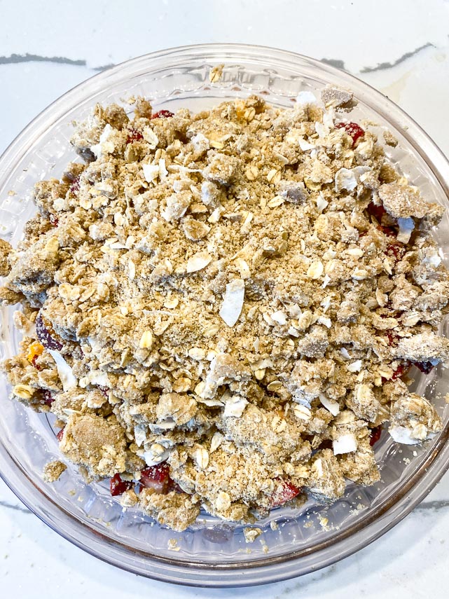 vegan oat crisp topping over fruit in pie dish before baking