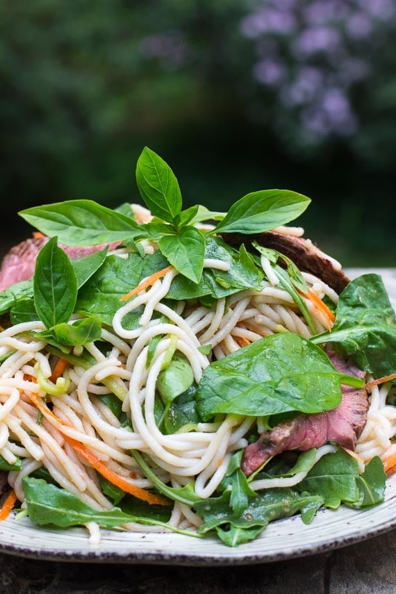 horizontal image of Low FODMAP Thai Basil Steak Salad on rustic round white plate