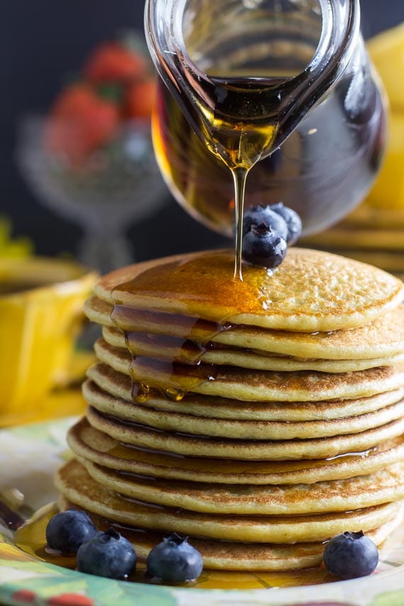 Big stack of low FODMAP high protein pancakes, syrup pouring over the side; a few blueberries alongside-4